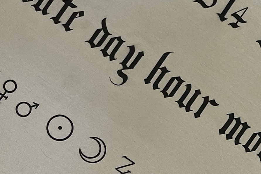 Close up of astrology glyphs and decoratve text on drawing paper