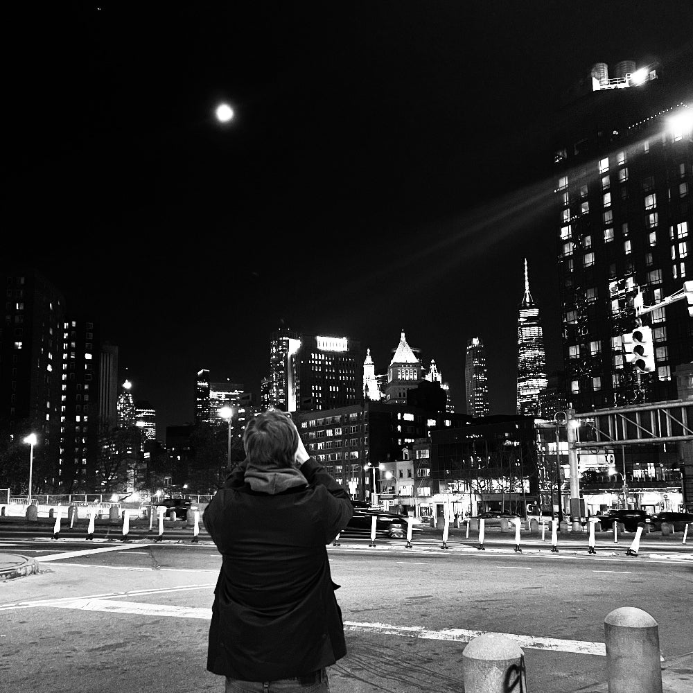Killian taking a photo of the moon and NYC skyline at night